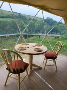 a table and chairs in a tent with a view at Pen-Y-Fan Glamping - Luxury Geodomes in Sennybridge +27 photos
