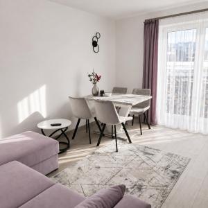 a white living room with a table and chairs at Grafitowe Apartamenty in Czarna Góra