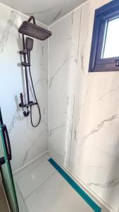 a shower with white marble walls and a shower head at Chalet met grote tuin en privé jacuzzi in Wijdenes +44 photos