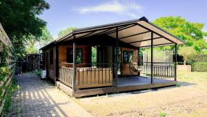 a small cabin with a porch in a garden at Chalet met grote tuin en privé jacuzzi in Wijdenes