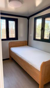 a bed in a room with two windows at Chalet met grote tuin en privé jacuzzi in Wijdenes