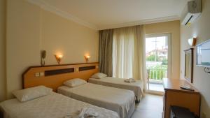 a hotel room with two beds and a window at Side Özgürhan Hotel in Side