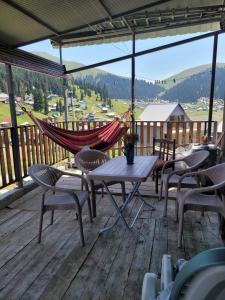 a hammock on a deck with a table and chairs at Cozy Mountain Chalet Bakhmaro in Chʼkhakoura