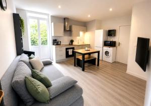 a living room with a couch and a kitchen at Appart'Hôtel Entre les 2 Roches in Prissé