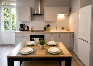 a kitchen with a wooden table with plates and wine glasses at Appart'Hôtel Entre les 2 Roches in Prissé