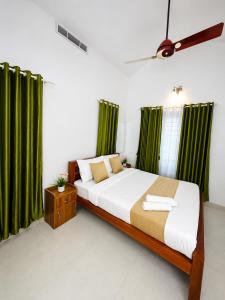a bedroom with a large bed with green curtains at Mist & Meadows Premium VIlla By STAYVA in Munnar