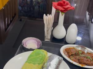 a table with a plate of food and a vase with a flower at Adhunik palace in Keonjhargarh +27 photos