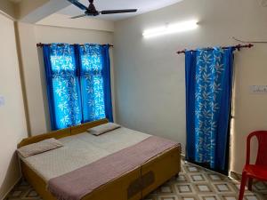 a bedroom with a bed with blue curtains and a ceiling at Sadyal Hotel And Restaurant in Tīra Sujānpur