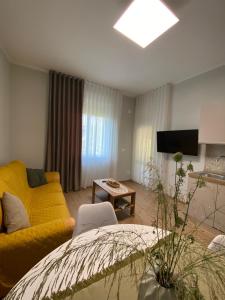 a living room with a yellow couch and a tv at Perla Blu House in La Spezia