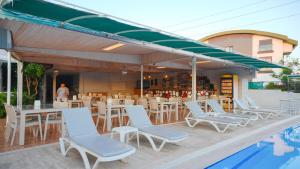 a restaurant with white chairs and tables and a pool at Side Özgürhan Hotel in Side