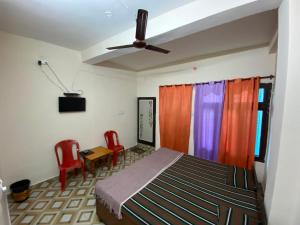a bedroom with a bed and two red chairs at Sadyal Hotel And Restaurant in Tīra Sujānpur