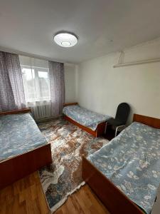 a room with two beds and a chair in it at Guest House Sveta in Saty