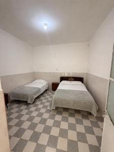 two beds in a room with a checkered floor at Los Olivos in Atlixco