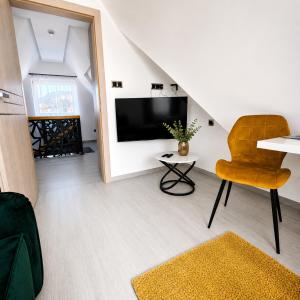 a living room with a television and a chair at Grafitowe Apartamenty in Czarna Góra