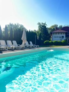 a pool with chairs and umbrellas next to a house at Kavaler inn hotel in Kuty