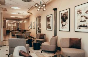 a waiting room with chairs and portraits on the wall at Leonardo Hotel Köln in Cologne