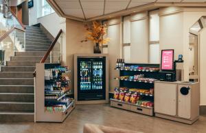 a store with a staircase and a aisle with drinks at Leonardo Hotel Köln in Cologne