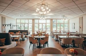 a restaurant with tables and chairs and a chandelier at Leonardo Hotel Köln in Cologne