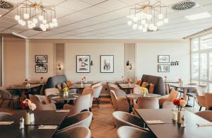 a dining room with tables and chairs and chandeliers at Leonardo Hotel Köln in Cologne