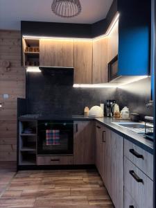 a kitchen with wooden cabinets and a stove top oven at Domek na Hubce 2 Blisko jeziora Velo Czorsztyn in Maniowy