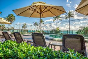 a group of chairs and umbrellas next to a pool at Ritz Suites Grand Hotel Boutique in Maceió