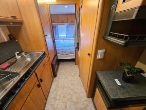 a small kitchen with a sink and a bedroom at Full Service Caravan 3 in Søborg