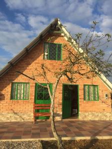 a brick house with green windows and a tree at La cabaña in Sotaquirá