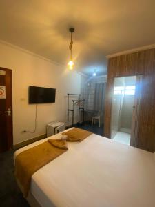 a bedroom with a large white bed and a flat screen tv at Santa Ana da Ribeira in SantʼAnna do Ipanema