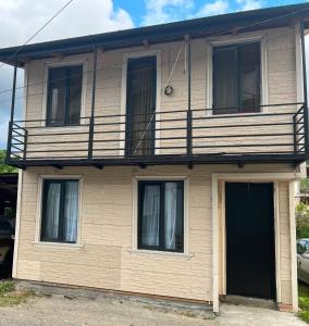 a yellow house with a balcony and a door at Casa nostra in Ambrolauri