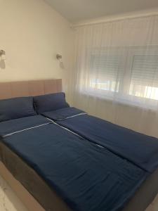 a bed with blue sheets in a bedroom with a window at Romantika 4 in Veliko Gradište