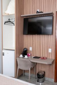 a room with a table and a television on a wall at Hotel Entre Rios in Pontalina