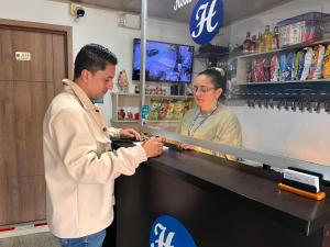 a man and a woman standing at a counter in a store at Hotel La Castellana in Manizales