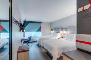 a hotel room with two beds and a desk at avid hotel Zeeland - Holland by IHG in Holland +53 photos