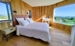 a bedroom with a white bed and a large window at Maison Ciaran in Trébeurden