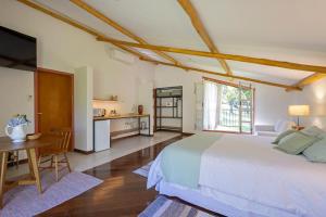 a bedroom with a bed and a table and a kitchen at Fazenda Montanhas do Japi in Jundiaí