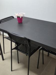 a black table with a black bench and a potted plant at מקום למשפחה in Kefar Tavor