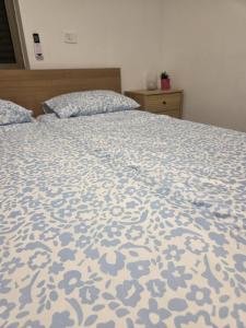 a bed with a blue and white comforter on it at מקום למשפחה in Kefar Tavor