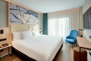 a hotel room with a bed and a blue chair at Sercotel Rosaleda Málaga in Málaga