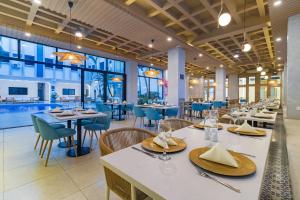 a restaurant with white tables and chairs and blue chairs at Hotel Presidente Beach Salinas in Salinas