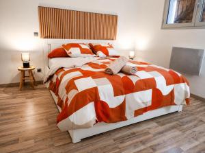 a bedroom with a bed with an orange and white comforter at ''Le Nid du Forez'' appartement 2 chambres , parking gratuit ,terrasse privative in Prétieux