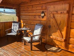 two chairs and a table on the porch of a cabin at Log cabin in rural surroundings in Stjoerdal