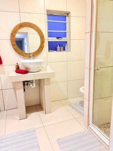 a bathroom with a sink and a mirror and a shower at West Coast comfortable stays in Cape Town +23 photos