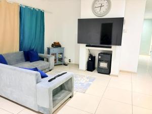 a living room with a couch and a clock on the wall at West Coast comfortable stays in Cape Town