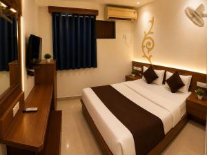 a bedroom with a large bed and a television at HOTEL CAMPUS in Ahmedabad