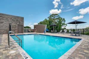 a swimming pool with tables and chairs and umbrellas at Staybridge Suites Crestview South by IHG in Crestview