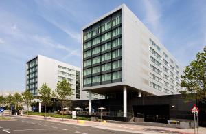 ein großes weißes Gebäude in einer Stadtstraße in der Unterkunft Steigenberger Airport Hotel Amsterdam in Schiphol