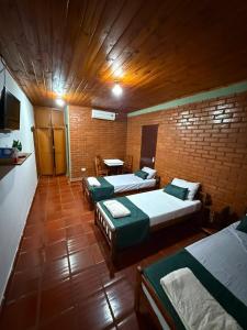 a room with three beds and a brick wall at Iguazú Garden Lodge in Puerto Iguazú