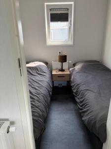 a small bedroom with two beds and a night stand at Luxe Chalet San Marco in Giethoorn