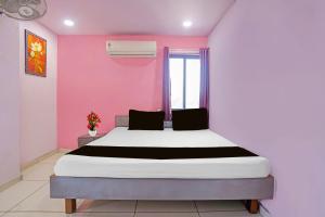 a bedroom with a bed in a pink room at Hotel O Unity Guest House in Dabhoi
