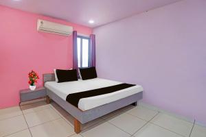 a bedroom with a bed with a pink wall at Hotel O Unity Guest House in Dabhoi